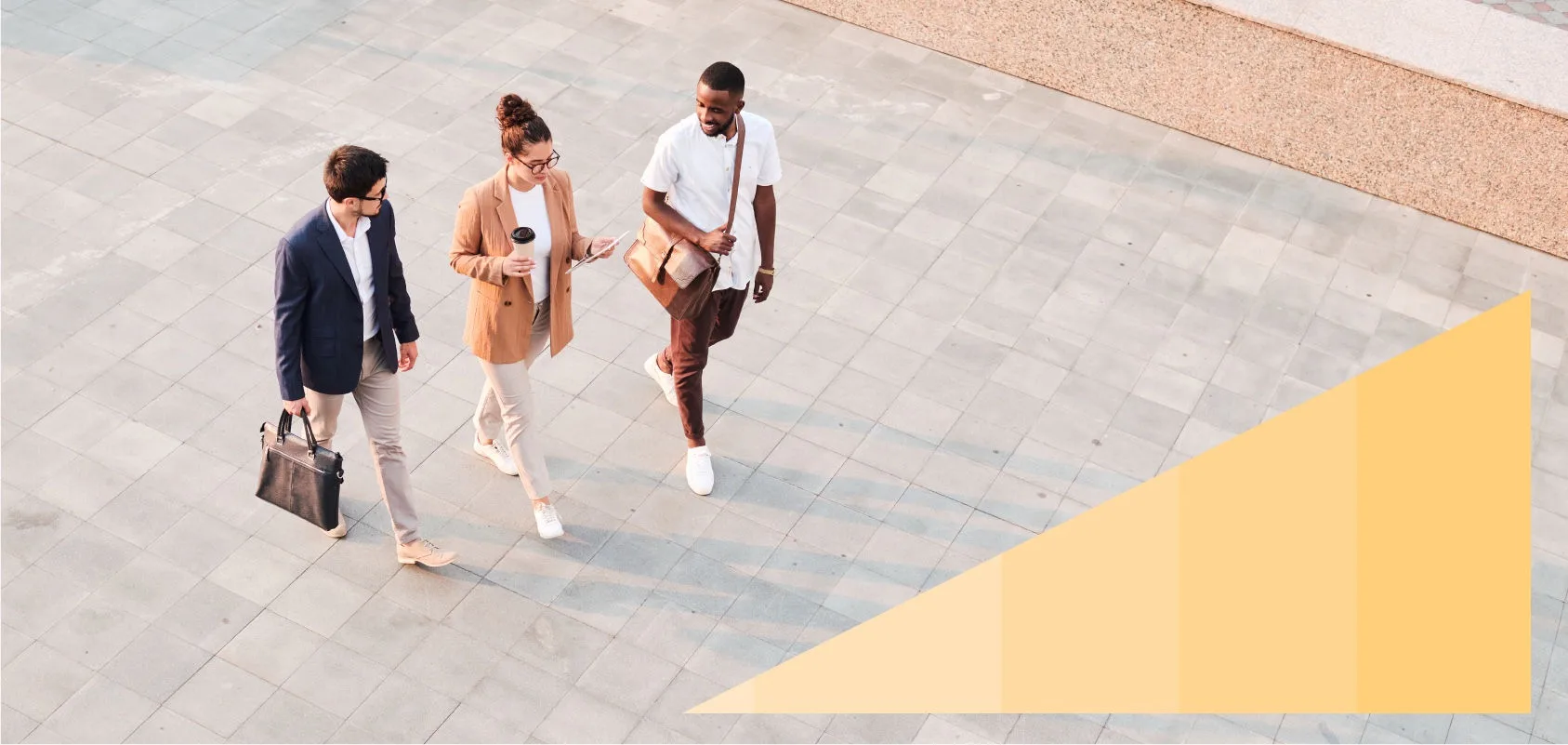 Two young men and a woman chat and walk across a stone court.